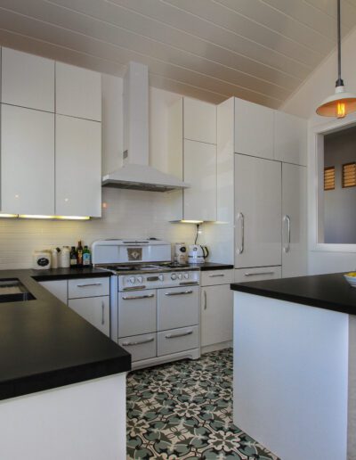 Bright modern kitchen with white cabinetry, black countertops, and patterned flooring.