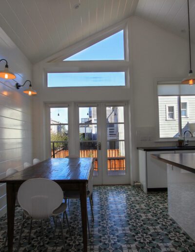 Bright, modern kitchen interior with high ceilings, pendant lighting, and patterned tile flooring.