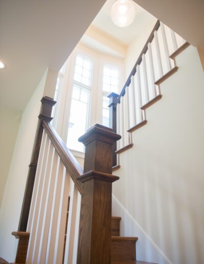 A wooden staircase with white balusters leading towards an upper-level window.