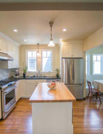 A modern kitchen with stainless steel appliances, white cabinets, and a central island.