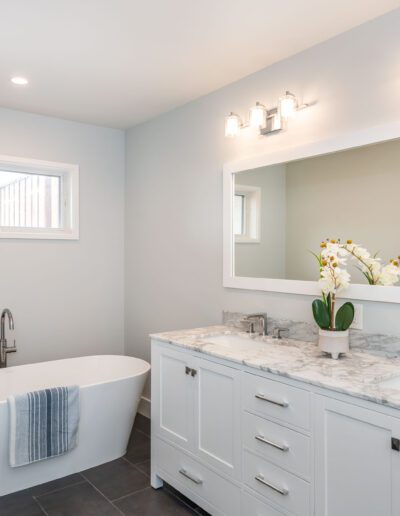 A modern bathroom with a freestanding tub, double vanity, and wall-mounted lights.