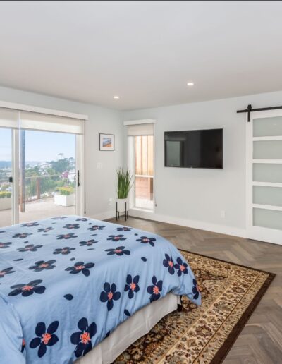 Spacious bedroom with sliding glass door, hillside view, and open concept leading to an adjoining bathroom with a barn door.