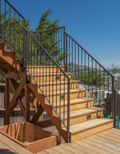 Wooden staircase on a deck with a view of the city skyline in the distance.