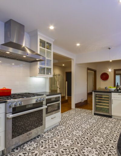 Modern kitchen interior with patterned flooring, stainless steel appliances, and white cabinetry.